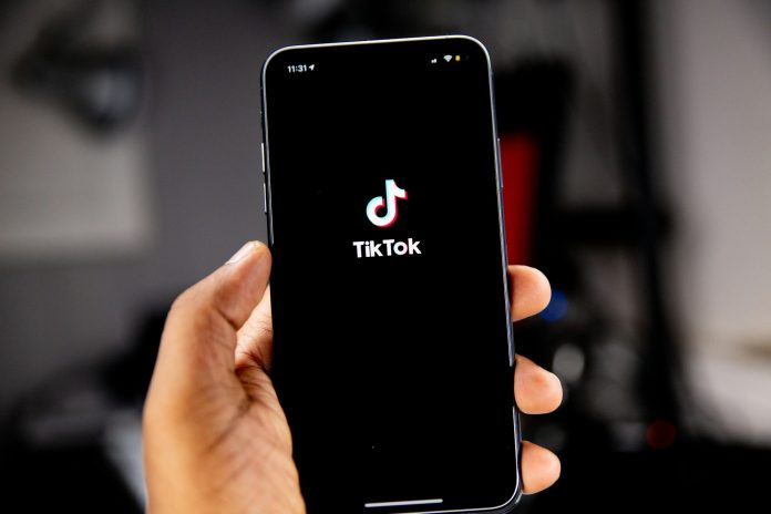 Pessoa segurando smartphone com o aplicativo TikTok aberto na tela.